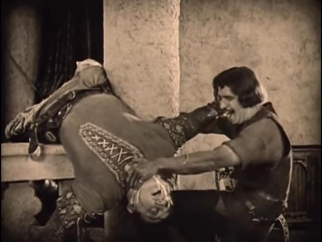 Douglas Fairbanks as Robin Hood, appearing to snap Gisbourne's neck